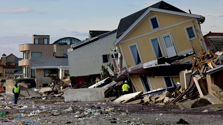A home badly damaged by superstorm Sandy rests on its...