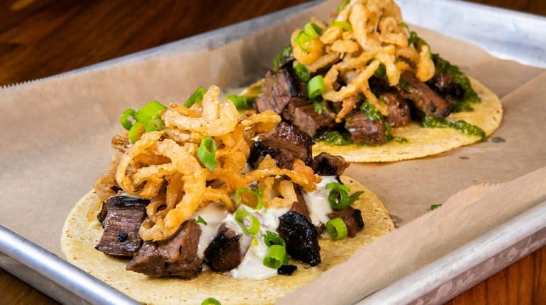 The Steakhouse taco (front) and chimichurri taco both come topped with...