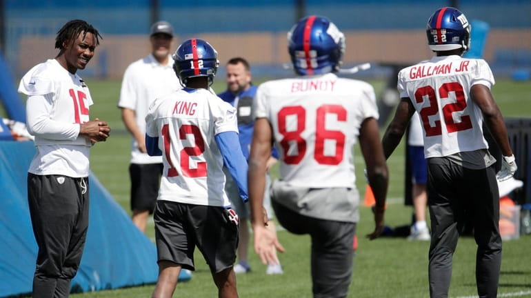 Giants receiver Brandon Marshall, left, watches as teammates warm up...