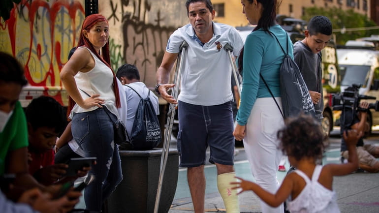 Eduardo Garcia, a migrant from Venezuela, stands with crutches alongside relatives outside...