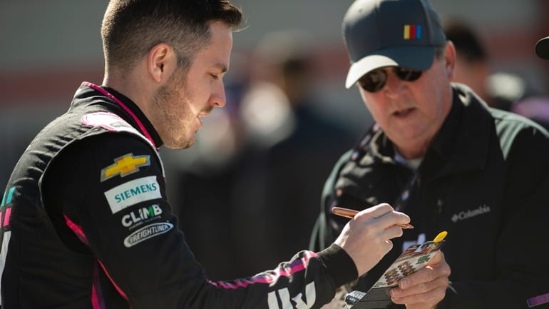 Driver Alex Bowman, left, signs autograph before qualifying for the...