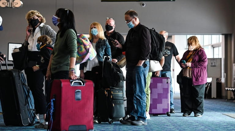 Passengers wait in line at a Frontier Airlines ticket booth...
