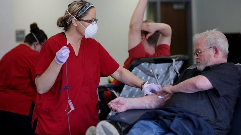 American Red Cross phlebotomist Andrea Riel holds pressure on Terry...