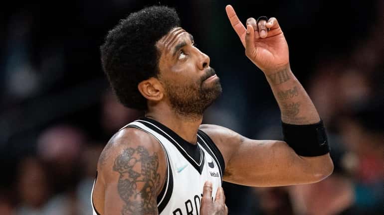The Nets' Kyrie Irving looks up and points to the...