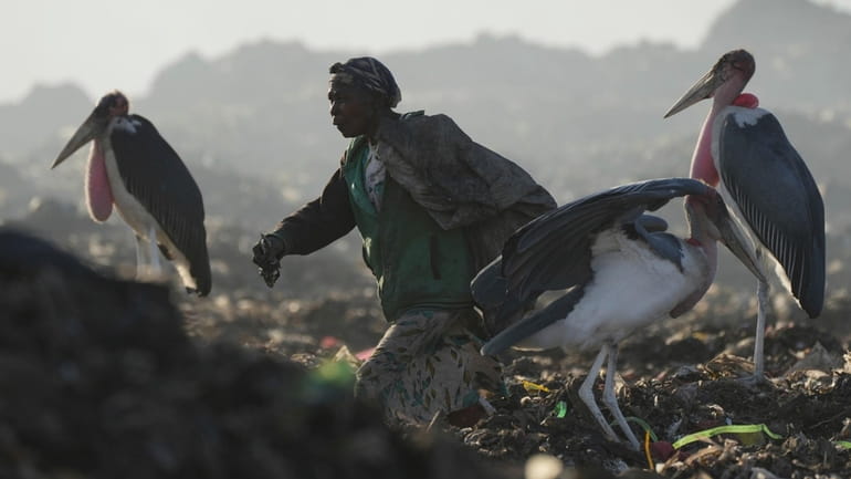 A woman who scavenges recyclable materials for a living, center,...