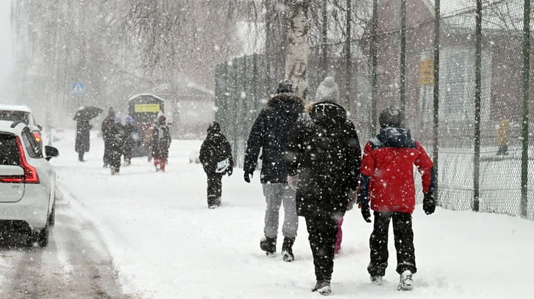Parents escort their children to the Viertola school in snow-fall...