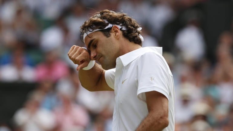 Roger Federer wipes his face during his men's singles quarterfinal...