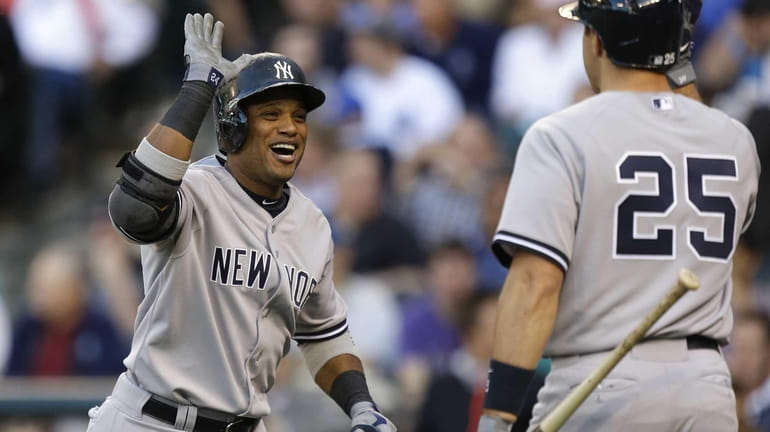 Yankees' Robinson Cano, left, greets Mark Teixeira, after Cano hit...