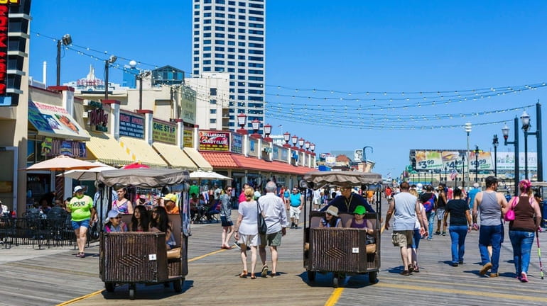 The Atlantic City Boardwalk's famous rolling chairs move along the...