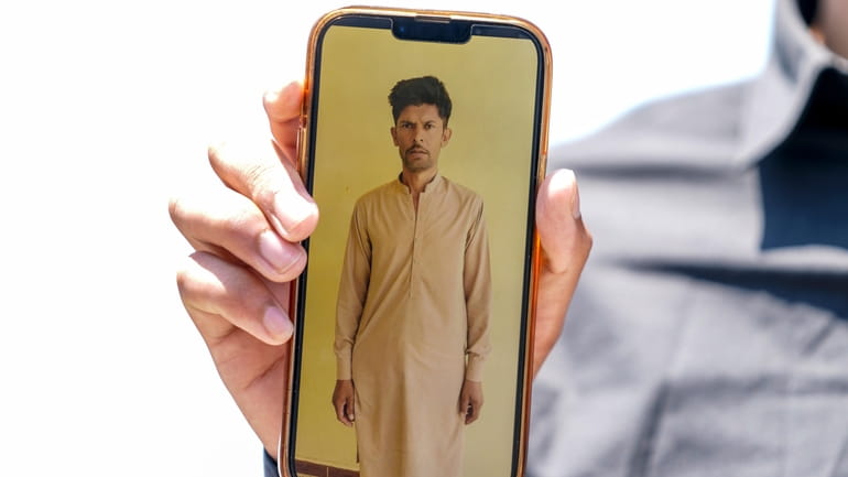 Zohaib Shamraiz holds up a photograph of his missing uncle,...