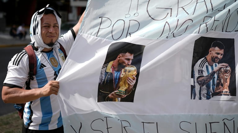 A fan of soccer star Lionel Messi helps hold up...