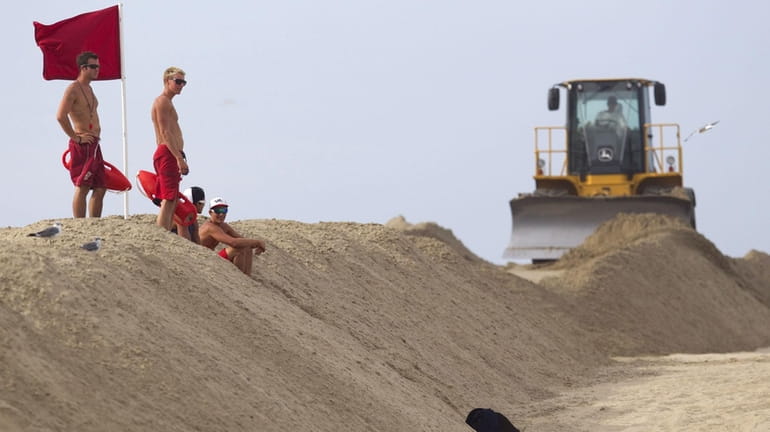 Lifeguards scan the water from the top of a sand...