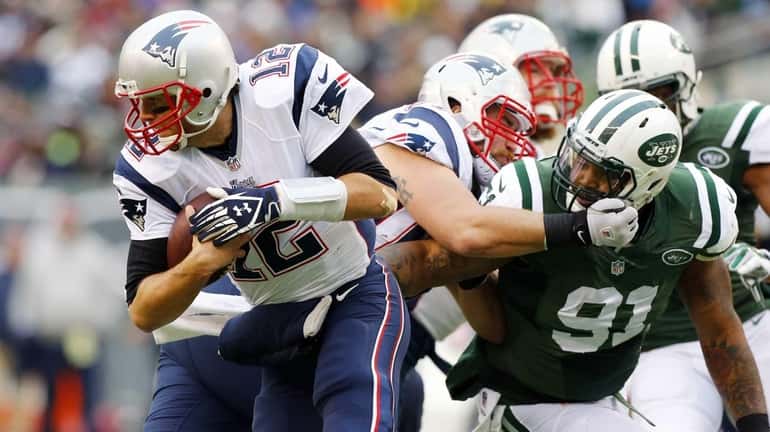 Tom Brady #12 of the New England Patriots is pressured...