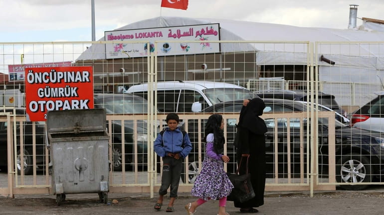 Syrians are seen at the Turkish border crossing of Oncupinar,...