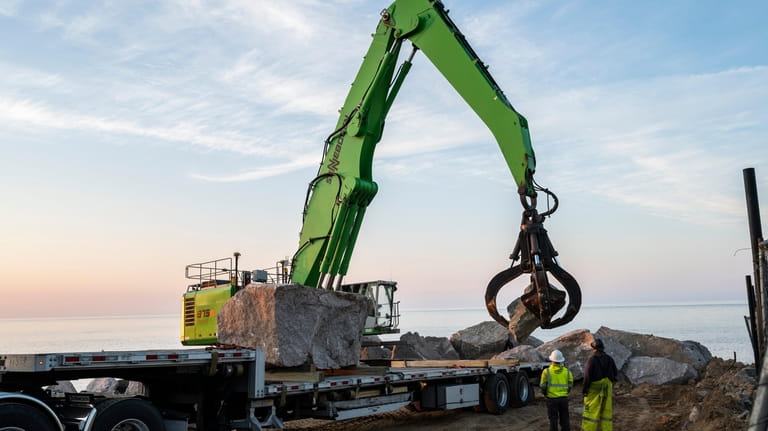 Workers unload large boulders Tuesday morning as they continue working on...