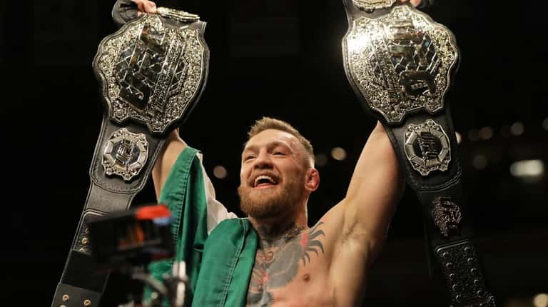 Conor McGregor holds up his title belts after beating Eddie Alvarez...
