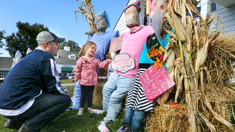 Visitors admire scarecrows at Stony Brook Village’s 32nd annual Halloween Scarecrow...