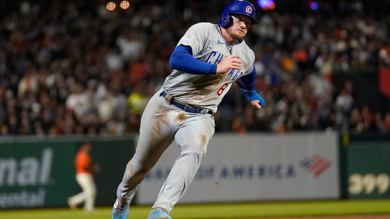 Chicago Cubs' Ian Happ rounds third on the way to...