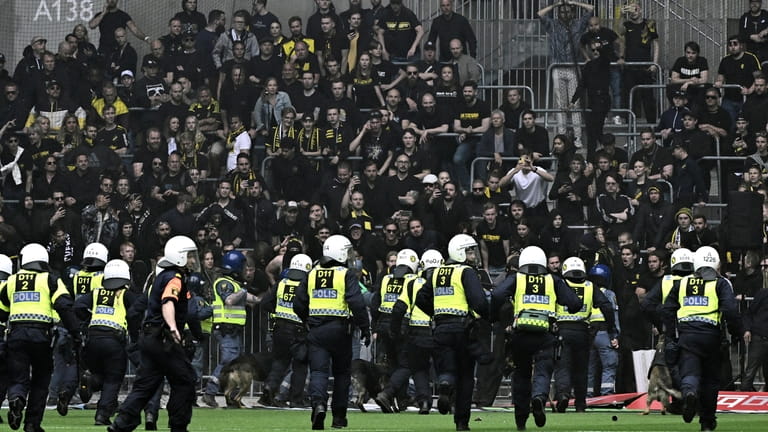 Police officers holding off AIK supporters trying to enter the...