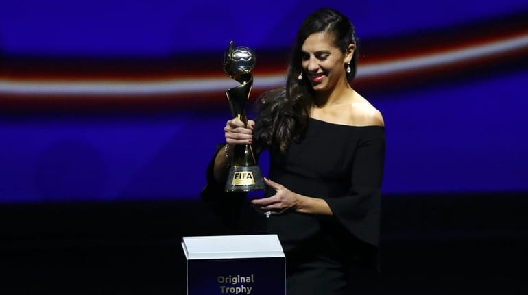 Carli Lloyd of the United States brings the trophy onto...