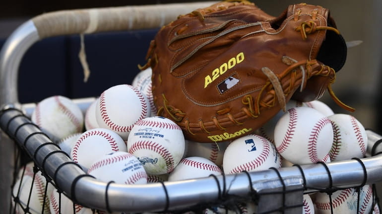A glove sits atop baseballs before the start of Game...