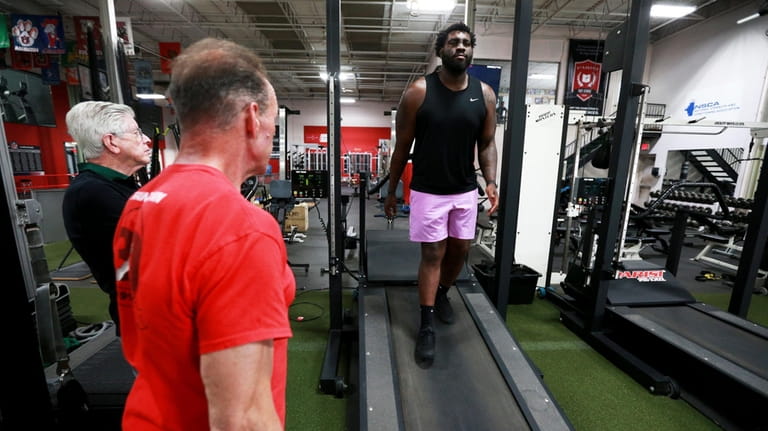 Jets lineman Mekhi Becton works out while watched by performance coach...