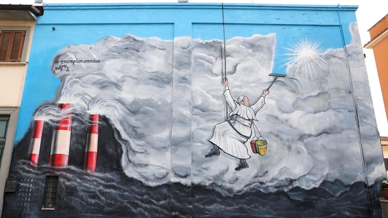 A graffiti depicting Pope Francis cleaning the sky from pollution,...