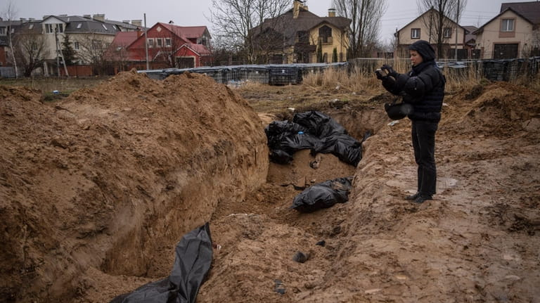 A journalist shoots video of a mass grave in Bucha.