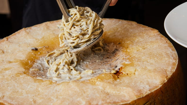 Taglierini flambéed in a Parmesan wheel with black truffle at Osteria...