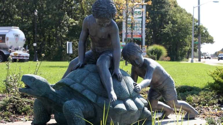A statue of a boy pushing a turtle in front...