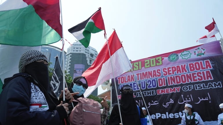 Protesters wave Palestinian flag during a protest in Jakarta, Indonesia,...