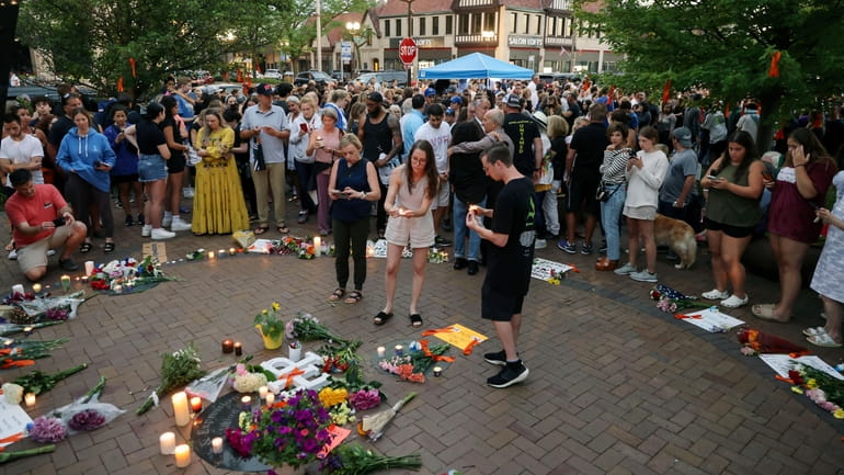 Mourners gather in downtown Highland Park, Ill., on Tuesday, a day after...