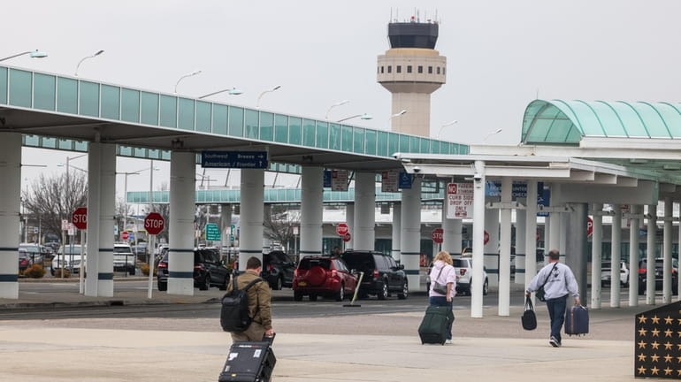 Travelers walk toward the main terminal at Long Island MacArthur Airport...