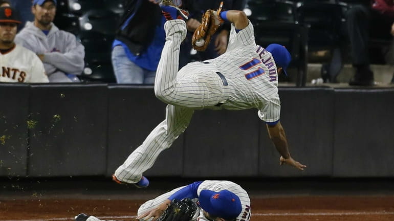 Ruben Tejada of the Mets is tripped up by Andrew...