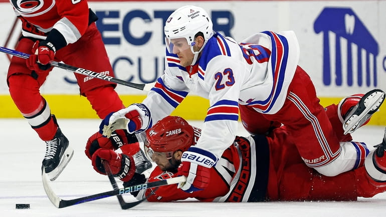 The Rangers' Adam Fox collides with and lands on the Hurricanes'...