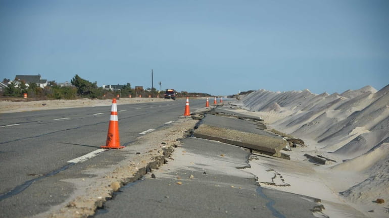 Dunes blow sand over the damaged section of Ocean Parkway...