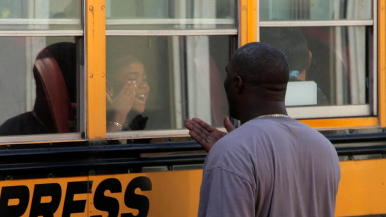 Anthony James, 45, waves through a school bus window to...