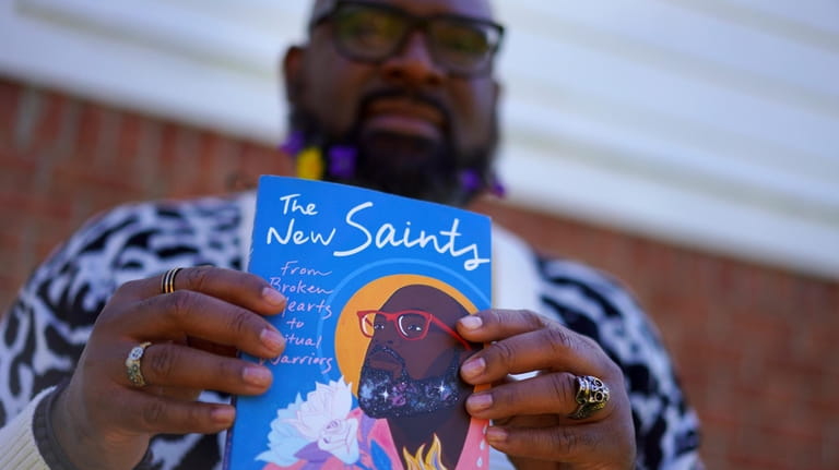 Lama Rod Owens holds his latest book, "The New Saints,"...