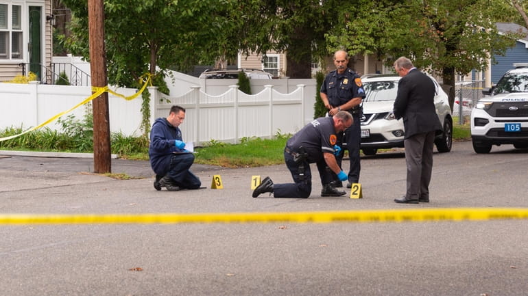 Suffolk County police officers and crime scene detectives investigate a...