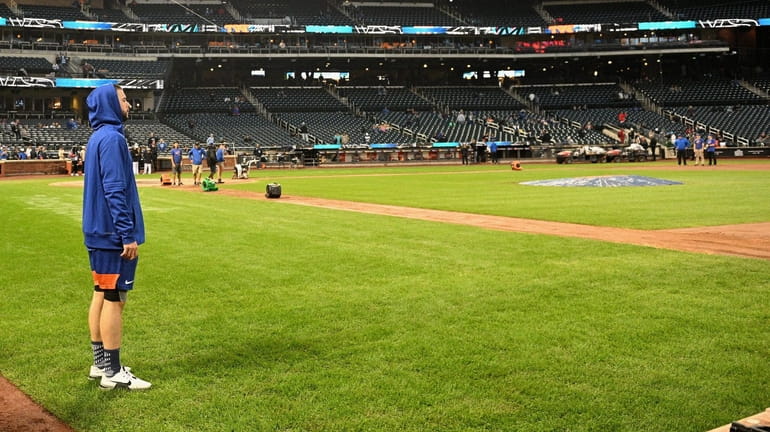 Mets starting pitcher Joey Lucchesi watches as the grounds crew...