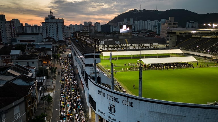 People wait in line to enter Vila Belmiro stadium where...
