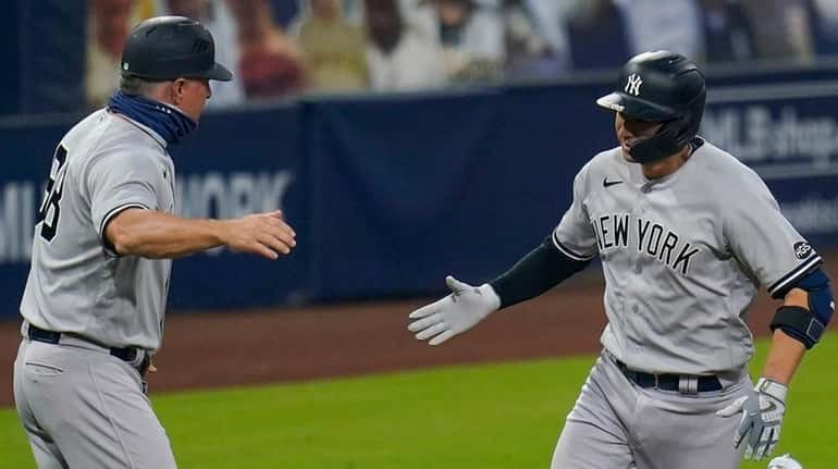 Yankees catcher Kyle Higashioka is congratulated by third base coach Phil...