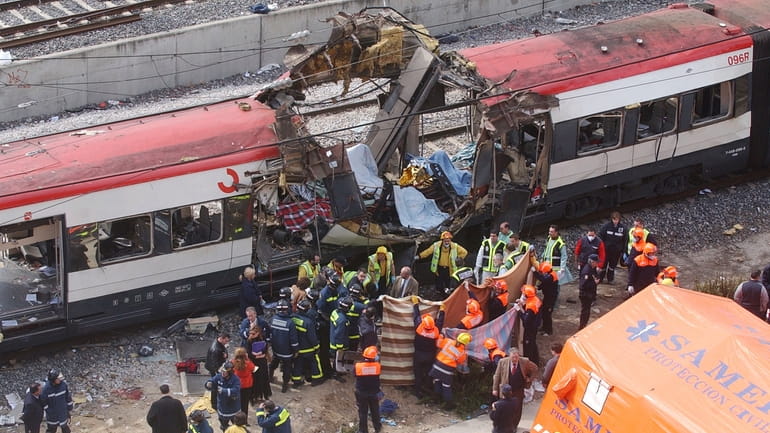 Rescue workers cover bodies alongside a bomb-damaged passenger train, following...