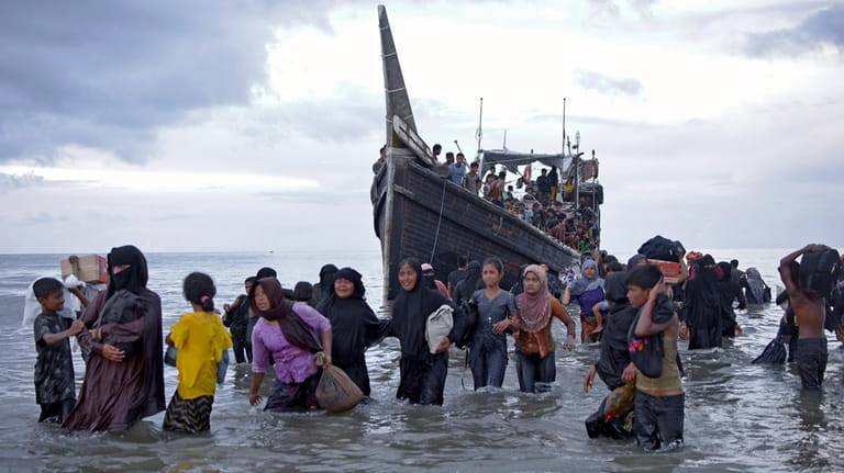 Ethnic Rohingya disembark from their boat upon landing on a...