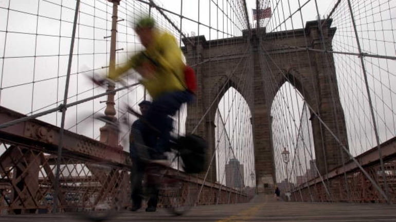 A man bikes on the Brooklyn Bridge.
