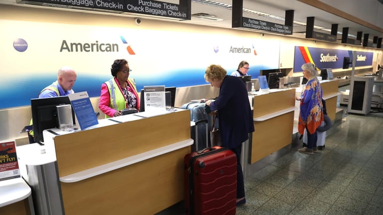 Passengers check-in for their flight for American Airlines from Long...