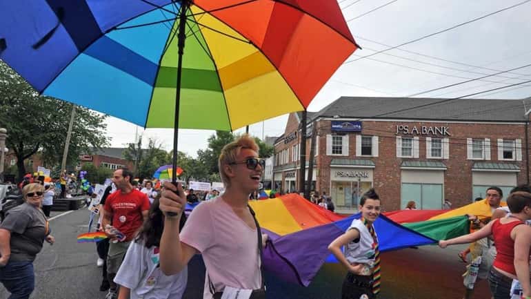 J.T., of Jericho, holds a rainbow-colored umbrella while helping to...