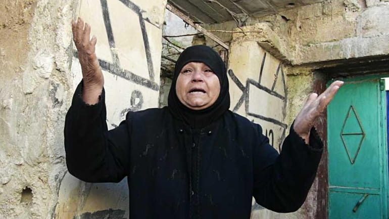 A Syrian woman reacts outside her house which attacked by...