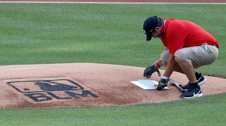 A Washington Nationals grounds crew member lays down a cleat...