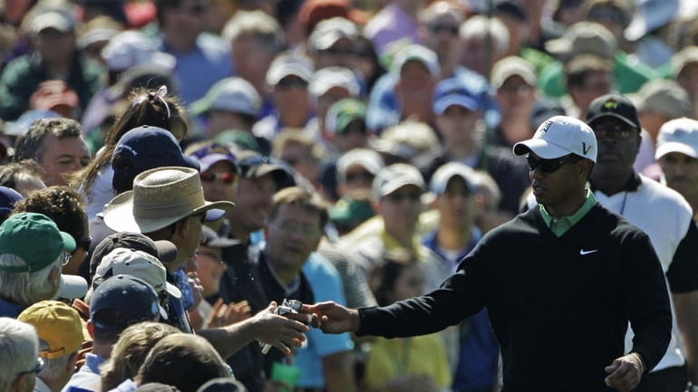 Tiger Woods gives his golfing gloves to a spectator after...